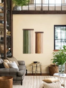 Detail of bohemian wood and woven cotton fringe wall hangings in a cozy living room decor