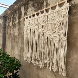 Macro detail of bohemian hand-woven tapestry showing cotton tassels and light wooden beads