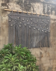 Detail of grey handmade bohemian tapestry with woven leaf patterns and wooden beads
