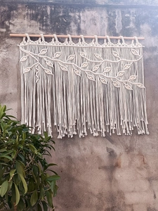Detailed view of macrame wall hanging with woven leaf patterns and long cotton tassels