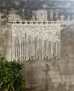 Macro detail of Bohemian macrame wall hanging with leaf texture and long cotton tassels