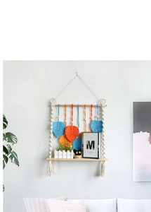 Detail of bohemian woven tapestry wall shelf featuring colorful feathers and wooden board