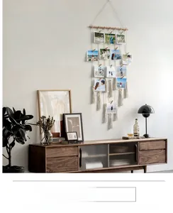 Detail of Bohemian woven tapestry photo wall with wooden clips and long tassels hanging on wall