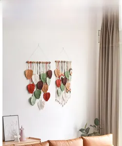 Detail of bohemian handmade woven leaf fringe tapestry on white wall with wood rods