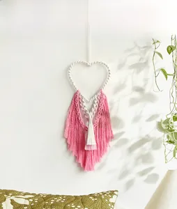Detail of bohemian heart-shaped macrame wall hanging with pink and white tassels