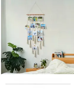 Detail of bohemian photo display with wooden clips, cotton cords and tassels decor