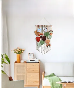 Detail of macrame wall hanging featuring hand-woven colorful leaves and photo clips