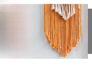 Detail of bohemian handmade woven wall tapestry with orange and white fringe