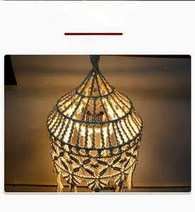 Detail of bohemian hand-woven cotton lamp shade with fringe and warm light effect