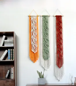 Detail of bohemian macrame wall hanging with handmade leaf fringe in orange, green, and red