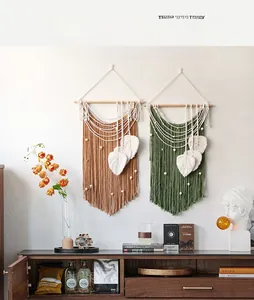 Detailed close-up of handmade Bohemian wall hanging with macrame leaf fringe and wooden rod