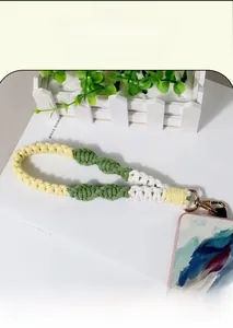 Detailed close-up of handmade woven lanyard in yellow, green and white with gold metal clasp