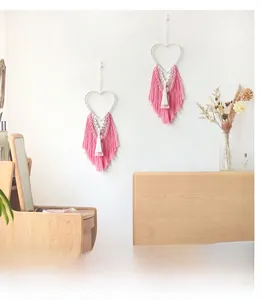 Detailed close-up of pink and white heart-shaped bohemian woven wall hangings with long tassels