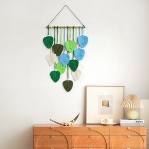 Bohemian macrame wall hanging with handmade woven leaf tassels on a natural wood branch