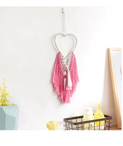 Detail of bohemian handmade macrame wall hanging with heart shape and pink tassels