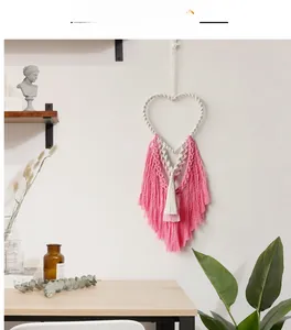 Detail of bohemian heart macramé wall hanging with pink and white cotton rope tassels