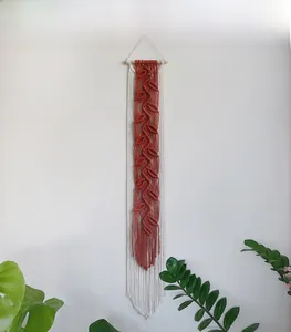 Detail of bohemian leaf woven tapestry with cotton fringes and wooden rod for wall decor