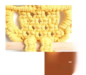 Close-up of yellow handmade bohemian macrame owl tapestry with detailed cotton weaving