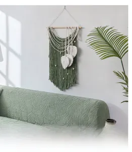 Close-up of light green knit sofa cover with 3D leaf pattern texture and fringe detail