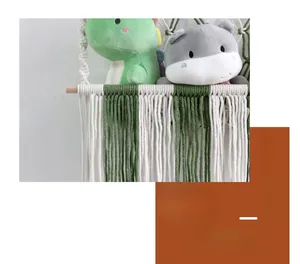 Detail of bohemian handwoven cotton toy hammock with wood pole and green tassels