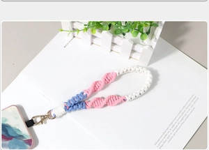 Detail of handmade braided phone wrist strap in pink and blue with gold spring buckle