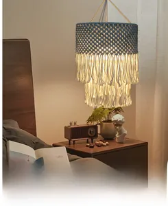 Detail of bohemian handmade woven lampshade with blue patterns and white tassels in bedroom