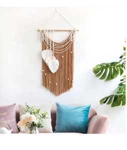 Detail of boho wall hanging featuring handmade leaf feathers and tassels with wooden beads