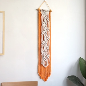 Bohemian handmade macrame wall hanging with orange tassels and leaf patterns