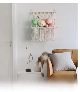 Detail of hand-woven cotton macrame toy storage shelf with tassels and wooden supports