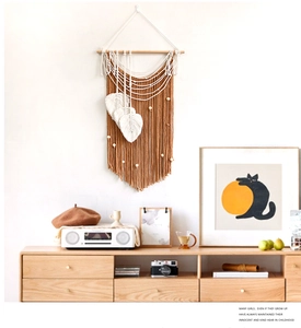 Detail of bohemian macrame wall hanging with white leaf feathers and wood beads