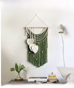 Detail view of handmade bohemian wall hanging featuring woven leaves and cotton tassels