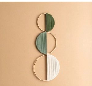 Detail of three-piece bohemian bamboo circle wall decor with olive green and white threads