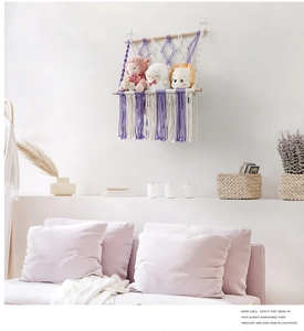 Detail of macrame toy hammock with purple cotton rope tassels and wooden poles