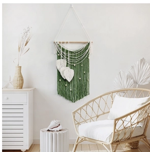Detail of dark green bohemian wall hanging with leaf fringe and decorative wooden beads