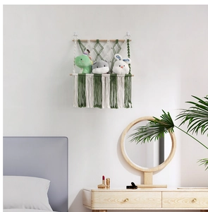 Detail of green and white macrame toy hammock with wood pole and long tassels