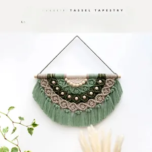 Detail of bohemian woven tapestry with green fringes and natural wooden beads