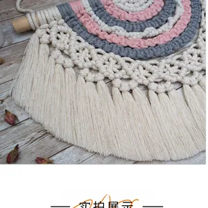 Detailed shot of handmade boho wall hanging with rainbow cotton ropes and tassels on wood