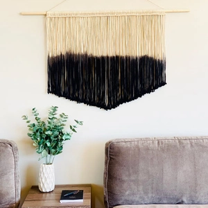 Détail d'une tenture macramé tissée main avec dégradé noir et baguette en bois massif