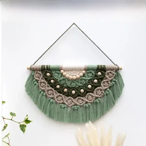 Detail of bohemian woven tapestry with green and beige cotton fringe and wood beads