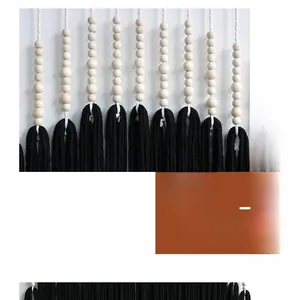 Detail of bohemian wall hanging featuring natural wooden beads and thick black cotton fringe