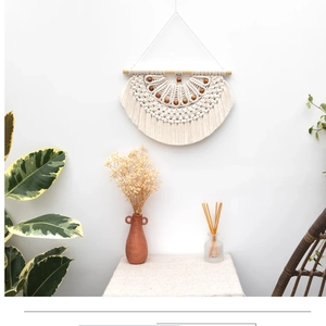 Detail of bohemian handmade woven wall hanging tapestry with wooden beads on a white wall