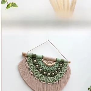 Detail of bohemian woven wall hanging with cotton tassels and wooden beads in green hues