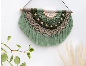 Detail of multi-layered green cotton macrame wall hanging with wooden beads and tassels