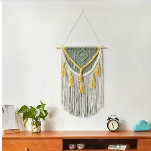 Detail of bohemian handmade cotton rope wall hanging tapestry with green and yellow tassels