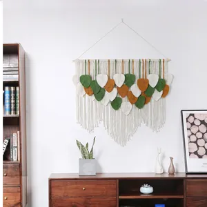 Detail view of handmade macrame leaf tapestry in white, green and caramel tones