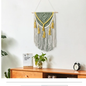 Detail of bohemian macrame wall hanging with sage green fringe and geometric cotton weaving