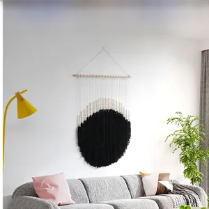 Detail of bohemian woven tapestry with geometric black and beige patterns on a wooden rod