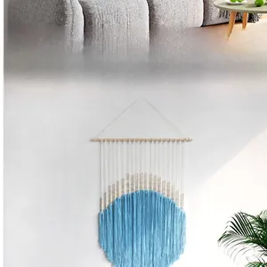 Close-up of Bohemian woven tapestry featuring white cotton ropes and light blue tassels