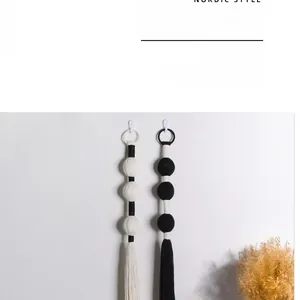 Macro detail of hand-woven black and white cotton tassel wall hanging in Nordic style