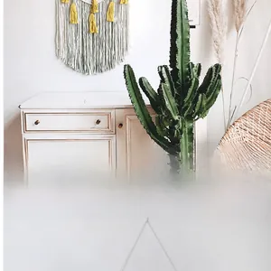 Detail of ivory macramé wall hanging with yellow tassels and wood support on white wall